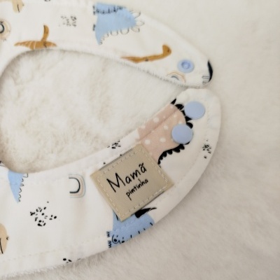 Babete redondo com padrão de dinossauros e etiqueta 