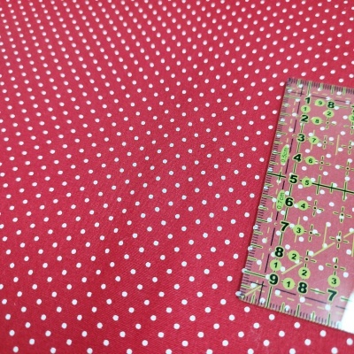 Tecido vermelho com bolinhas brancas e régua transparente com marcações.