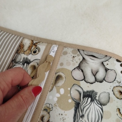 Capa ou bolsa com padrão de animais africanos e fecho zipper branco.