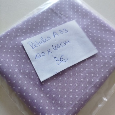 tecido lilás com pontos brancos embalado em plástico com etiqueta de papel
