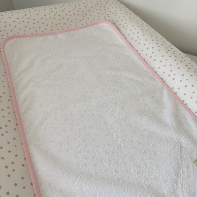 toalhete branco com borda rosa sobre superfície com padrão de estrelas cor-de-rosa