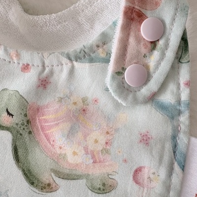 Babete de bebé com estampa de tartaruga e fecho pressionado rosa