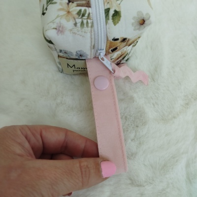 Estojo floral branco com fecho de correr e alça rosa segurada por mão