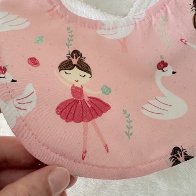 Babete rosa para bebé com padrão de bailarinas e cisnes