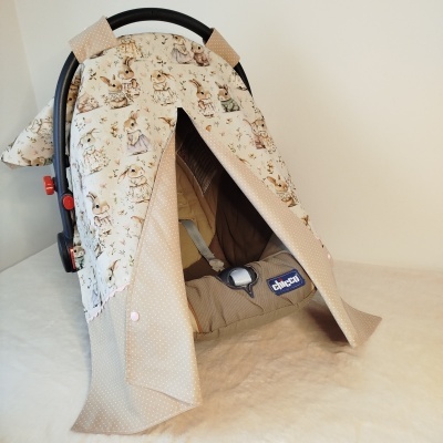 Cadeira auto Chicco com capa protetora estampada de coelhinhos e tecido bege com pequenos pontos brancos