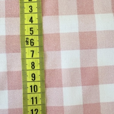 Fita métrica amarela sobre tecido quadriculado rosa e branco
