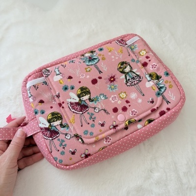 Bolsa rosa com padrão de fadas e flores sobre superfície branca