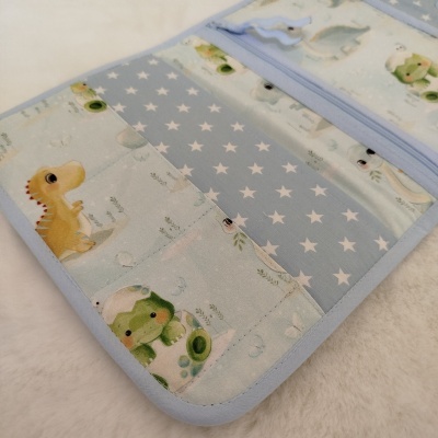 Organizador de tecido azul claro com estampa de estrelas brancas e desenhos infantis de dinossauros e sapos