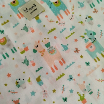 Tecido branco com padrão colorido de lhamas e flores e etiqueta 'Mamã planinhos'