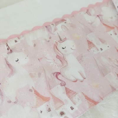 Tecido rosa com unicórnios e castelos, borda rosa ondulada