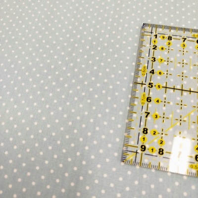 Tecido azul claro com pintas brancas e régua transparente com marcações amarelas.