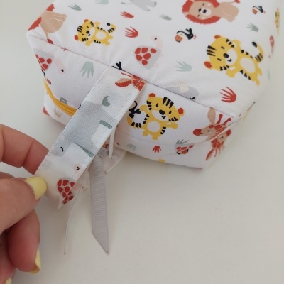 Mochila de tecido com estampa de animais coloridos e alças ajustáveis.