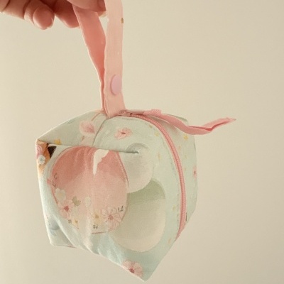 Bolsa floral pequena com fecho rosa e alça rosa segurada por mão
