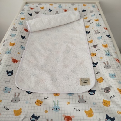 Pano branco e colchão de bebé com padrão colorido de animais