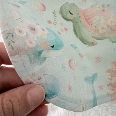 tecido com padrão infantil de golfinho azul e tartaruga verde em tons pastel
