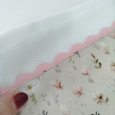 tecido branco com acabamento rosa ondulado e tecido floral com mão