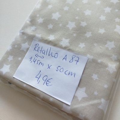 Tecido bege com estrelas brancas embalado com etiqueta manuscrita.