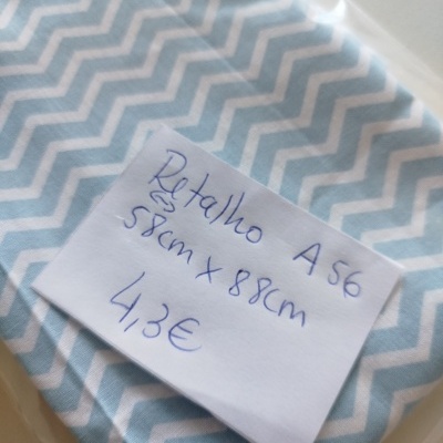 Retalho de tecido azul claro com padrão zig zag branco embalado em saco plástico