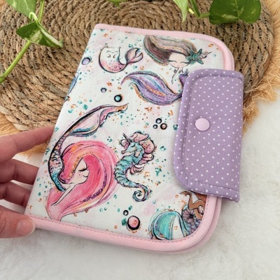 Bolsa de tecido com padrão de sereias coloridas e fecho lilás com bolinhas