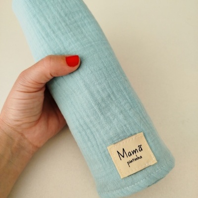 Tecido azul claro com etiqueta Mamã pintinha segurado por uma mão