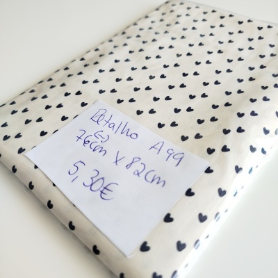 Tecido branco com padrão de corações pretos embalado com etiqueta manuscrita.
