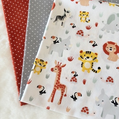 Tecidos de algodão com padrão de animais e bolinhas sobre superfície branca macia