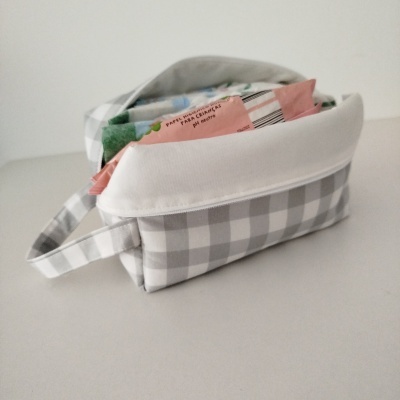 Mala xadrez cinzento e branco com embalagem rosa de papel higiénico para crianças no interior