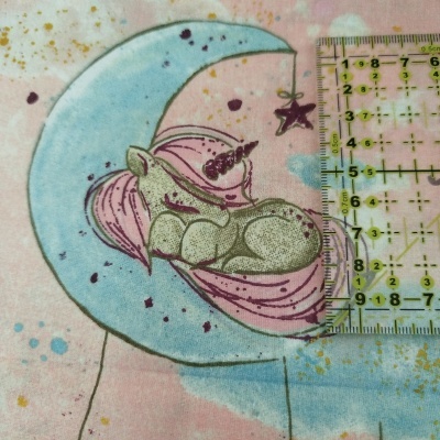 Tecido rosa com desenho de unicórnio a dormir numa lua azul e régua ao lado