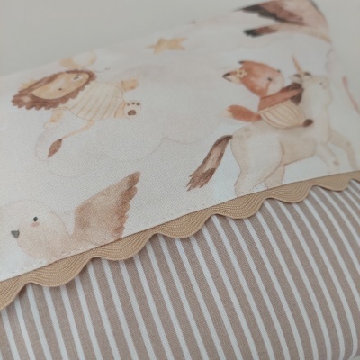 Detalhe de tecido branco com estampado de animais e borda ondulada bege sobre superfície riscada