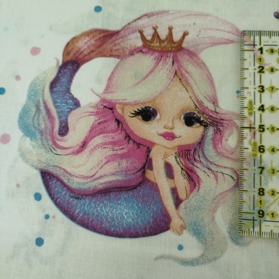 Estampa de sereia rosa e lilás em tecido branco com régua ao lado para escala.