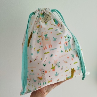 Saco de tecido com padrão colorido de lhamas e cordões azuis