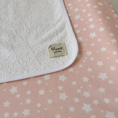 Toalha branca em algodão com etiqueta مربä pintinha sobre tecido rosa com estrelas brancas
