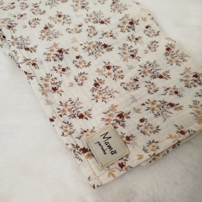 tecido branco floral com etiqueta Mamã pirinha sobre superfície branca macia