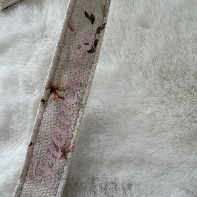 Correia floral com texto Francisca Cañ sobre fundo branco peludo