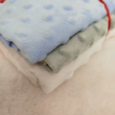 Três mantas felpudas em azul, cinzento e branco amarradas com laço vermelho