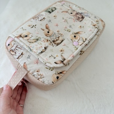 Mochila infantil bege com padrão de coelhos em roupas florais e flores pequenas