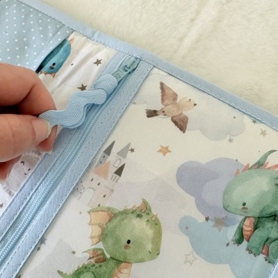 Capa azul clara com dinossauros e pássaros em tecido com fecho de correr