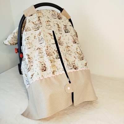 Capa para alcofa de bebé com padrão de coelhos vestidos e parte inferior bege de bolinhas brancas.