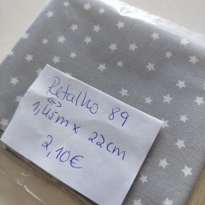 Tecido cinzento com estrelas brancas embalado e com etiqueta de preço