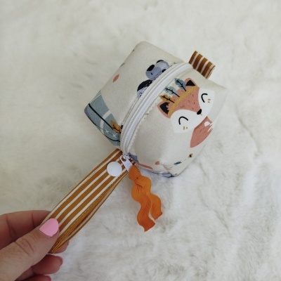 Bolsa pequena de tecido com padrão de raposa e alça listrada sobre superfície branca macia