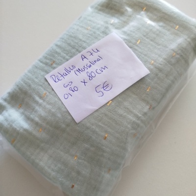 Retalho de tecido de musselina verde claro com pontos dourados embalado em plástico com etiqueta