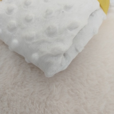 Manta branca macia com textura em relevo e borda amarela