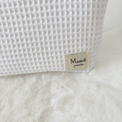 Tecido branco com textura quadrada e etiqueta com texto Mamã pintinha