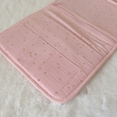 Carteira ou organizador cor-de-rosa com padrão de pontos dourados em superfície branca felpuda