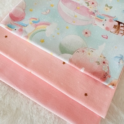Tecidos infantis com estampado de unicórnios e balões e tecido rosa com estrelas pequenas.
