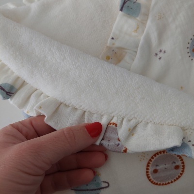 Toalha ou fralda de bebé branca com estampado de planetas e estrelas e detalhe de volante