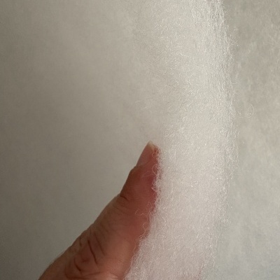Mão segurando material branco fibroso, semelhante a espuma ou enchimento