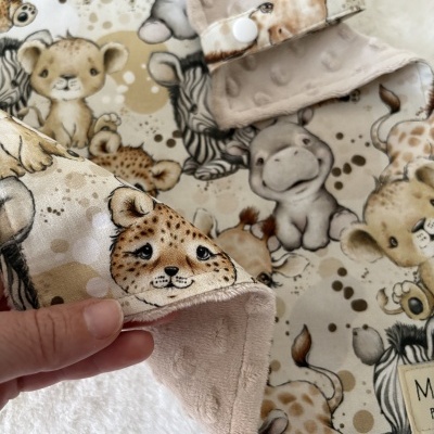 Cobertor infantil com padrão de animais em tons castanhos e bege com botão branco