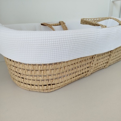 Cesto retangular em palha com forro branco e alças na superfície clara