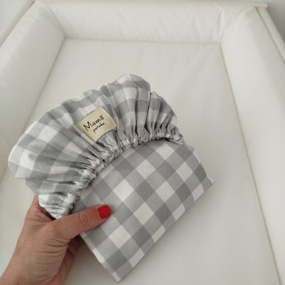 Capa elástica xadrez cinza e branco com etiqueta Mamã pintinha sobre fundo branco acolchoado